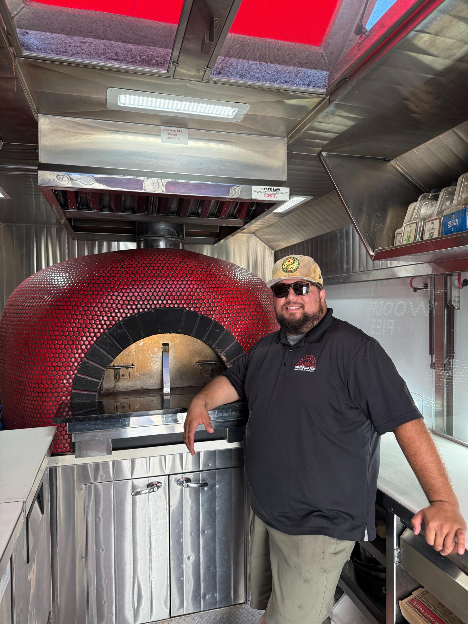 Man in front of wood fire pizza oven